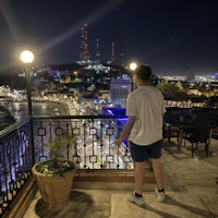 a man standing on a balcony overlooking a city at night